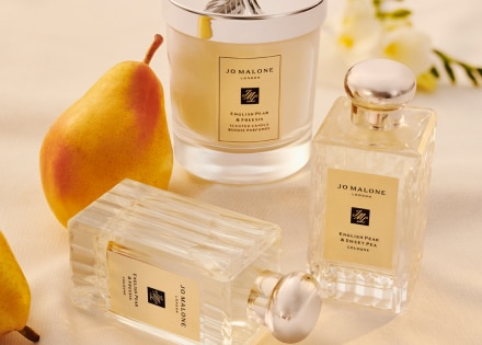 Cologne e candela English Pear and Freesia su un tavolo con una pera